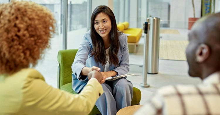 Two employees greet a candidate in a business office setting