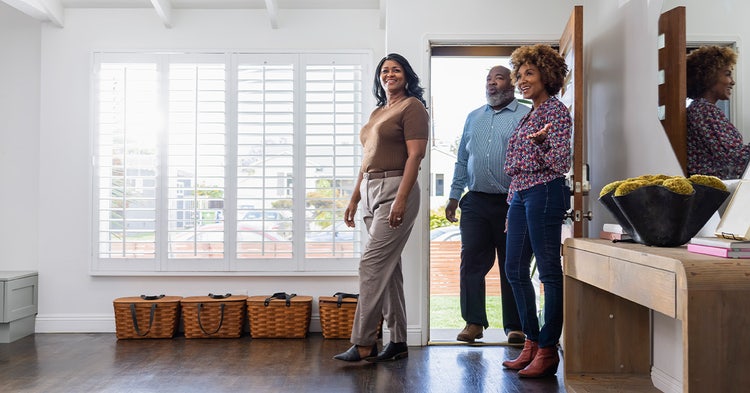 Young female REALTOR® discussing with mature couple while showing home