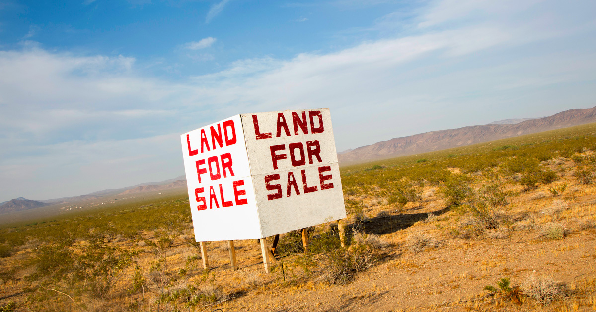 Biển báo "Đất để bán" bên đường, tự làm trên một cánh đồng trống lớn.